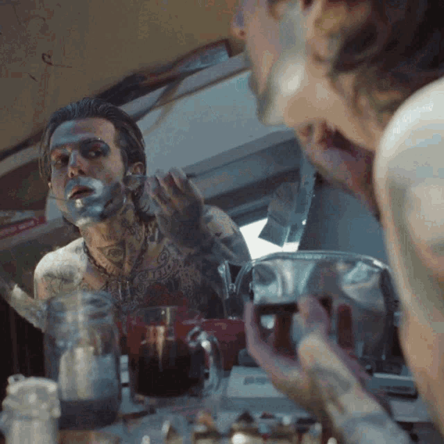 a man with a tattoo on his chest is shaving