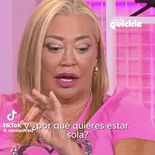a woman is wearing a pink shirt with a heart on it and is talking in spanish .