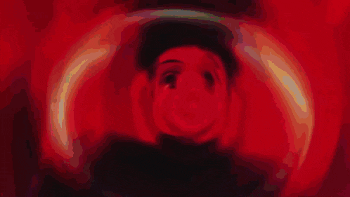 a close up of a person 's face with a red background and a light coming out of it .