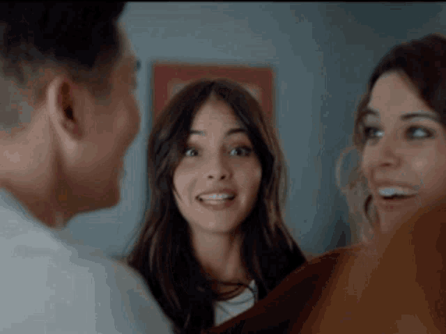 a man and two women are talking to each other and smiling