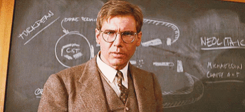 a man wearing glasses stands in front of a blackboard that says neoclassic
