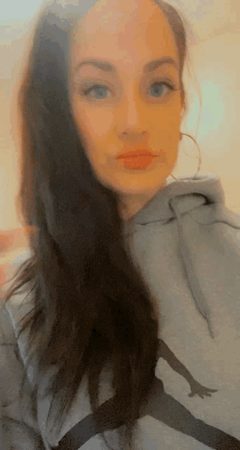 a woman is wearing a grey hoodie with a picture of a skateboarder on it