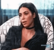 a woman is sitting in a chair wearing a choker and a jacket .