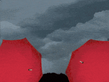 three men in yellow raincoats holding red umbrellas in the rain