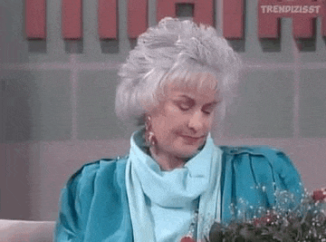 a woman with gray hair and a blue jacket is sitting on a couch .