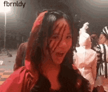 a woman in a red riding hood costume with claw marks on her face is smiling .