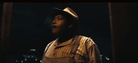 a man wearing overalls and a hat is screaming with his arms outstretched