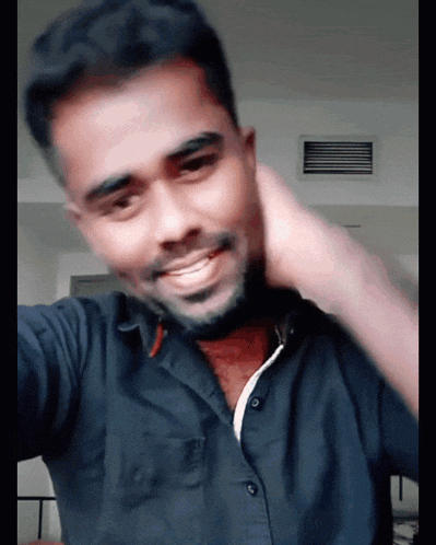 a man wearing a black shirt is smiling and scratching his neck