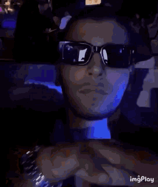 a man wearing sunglasses is making a gesture with his hands .