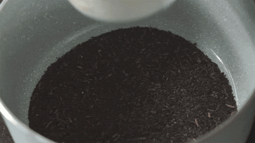 a bowl of milk is being poured into a pile of black rice