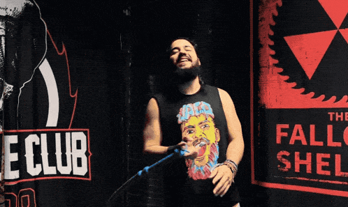 a man singing into a microphone in front of a banner that says the club