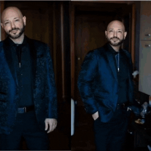 a man in a blue suit is standing in a room with his hands in his pockets .