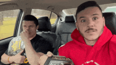 two men in a car one wearing a red hoodie that says i 'm not a bully