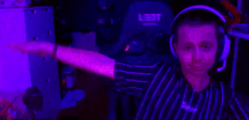 a man wearing headphones and a striped shirt is sitting in a dark room with a purple light behind him .