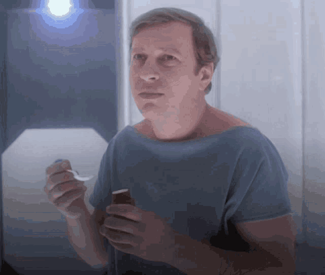 a man in a blue shirt is holding a spoon in his right hand