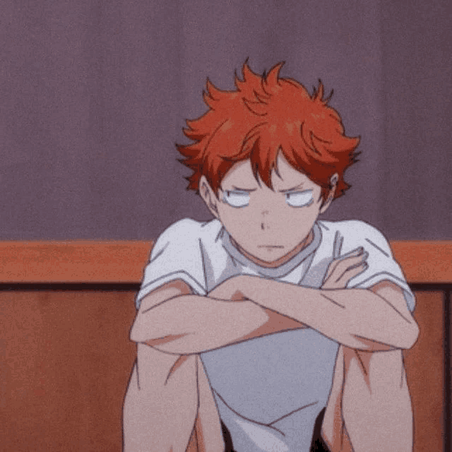 a boy with red hair is sitting with his arms crossed and his eyes closed