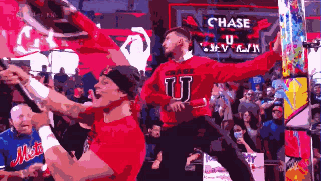 a man in a red sweater with the letter u on it stands in front of a crowd
