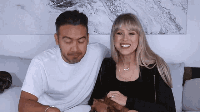 a man and a woman are sitting next to each other on a couch with a dog .