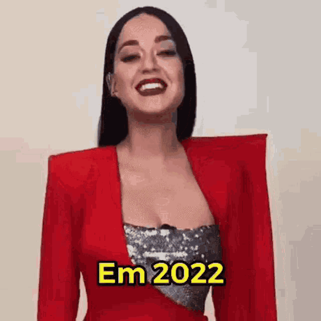 a woman is wearing a red jacket and a sequined dress and smiling .
