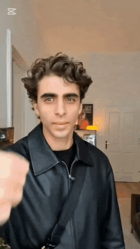 a young man wearing a black leather jacket and a black shirt