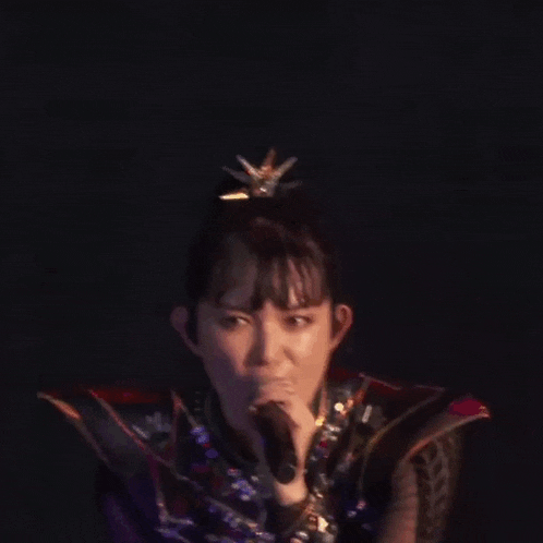 a woman in a costume is singing into a microphone on stage .