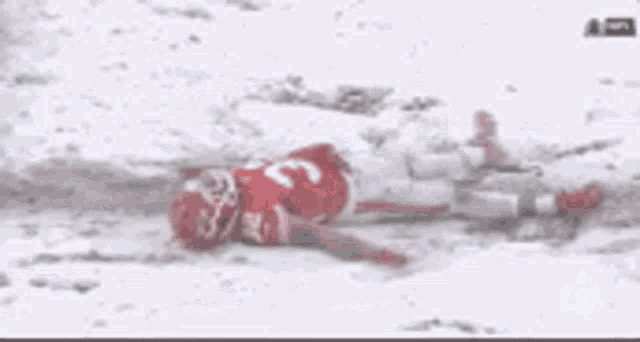 a football player is laying in the snow after being injured during a game .