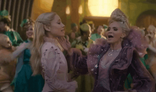a woman in a purple dress is dancing with another woman in a pink dress