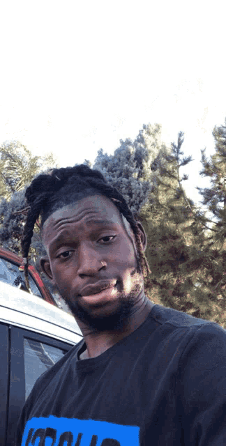 a man with dreadlocks is wearing a black shirt with a blue logo that says ' i 'm cool '