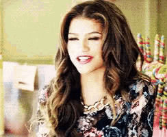 a woman with long hair is wearing a floral top and a necklace .