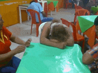 a woman sits at a table with her head on the table