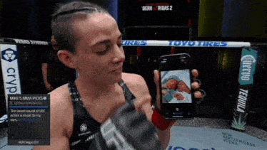 a woman holding a cell phone with a picture of two babies on it