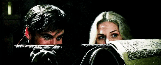 a man and a woman are hiding behind a blanket .