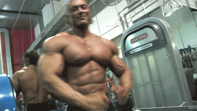 a man flexes his muscles in front of a machine that says impact on it