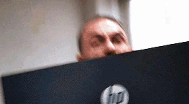 a man is peeking over an hp laptop