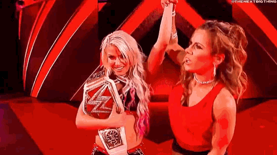 a couple of women standing next to each other on a stage holding a wrestling championship belt .