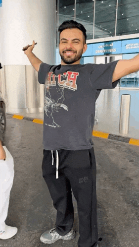 a man with his arms outstretched is wearing a t-shirt that says aitch