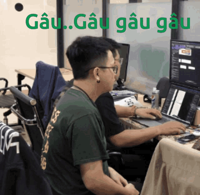 two men are sitting at a desk with a sign that says gau