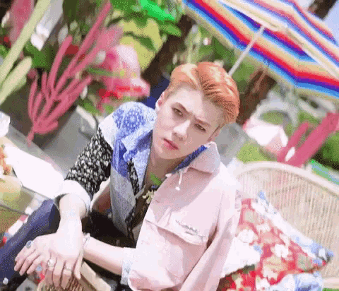 a young man with red hair is sitting under an umbrella on a couch .