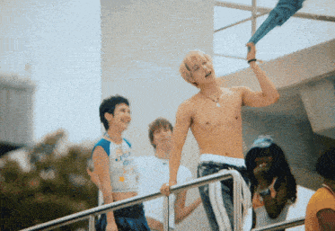 a man without a shirt is standing on a railing with a woman laughing behind him