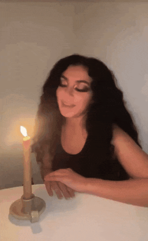 a woman sitting at a table with a lit candle