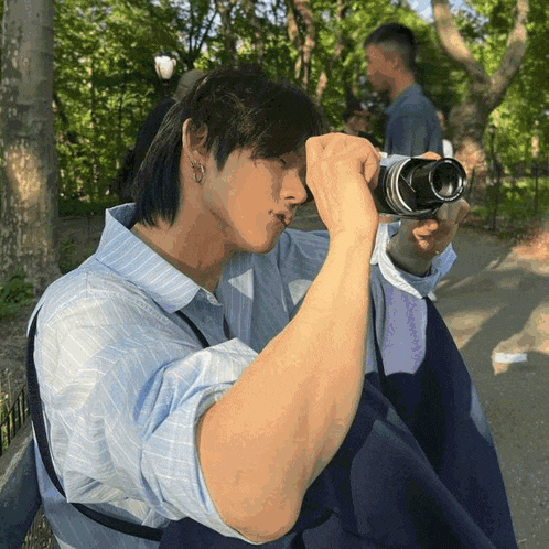 a man is taking a picture with a camera in a park