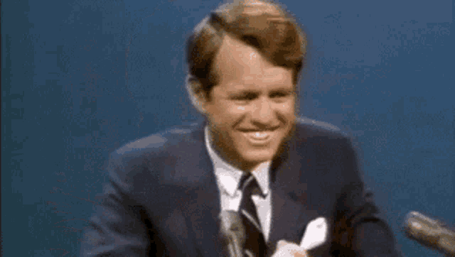 a man in a suit and tie is talking into a microphone .