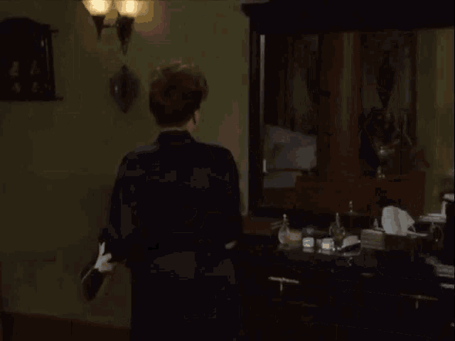 a woman is standing in front of a mirror in a room