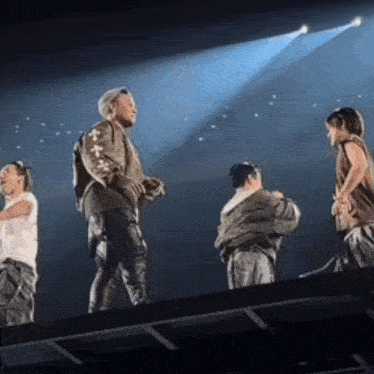 a group of people are standing on top of a stage in front of a spotlight .