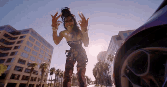 a woman is standing in front of a car and giving the peace sign