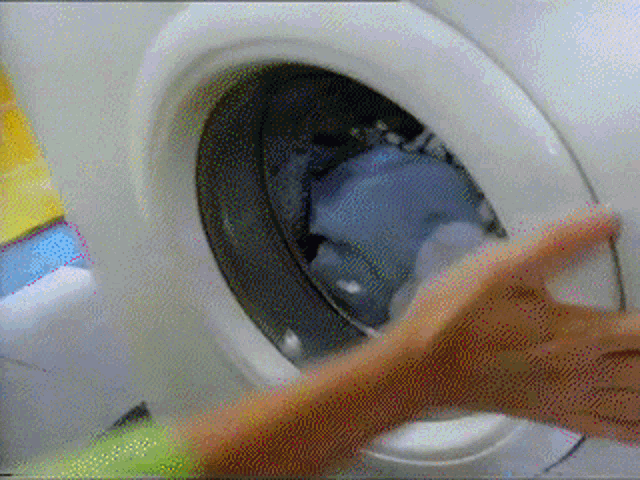 a person 's hand is reaching into a washing machine