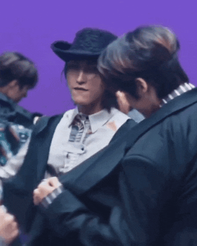 a man in a cowboy hat is talking to another man in a suit