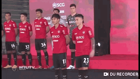 a group of soccer players are standing in a line wearing red jerseys with scg written on them