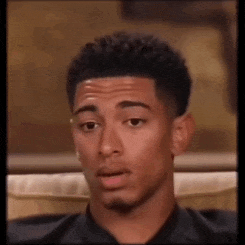 a man is sitting on a couch making a funny face .