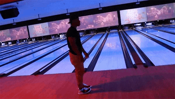 a man stands in a bowling alley with a sign that says save $ 80 over